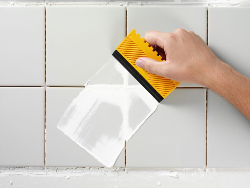 Someone applying grout to shower tiles.