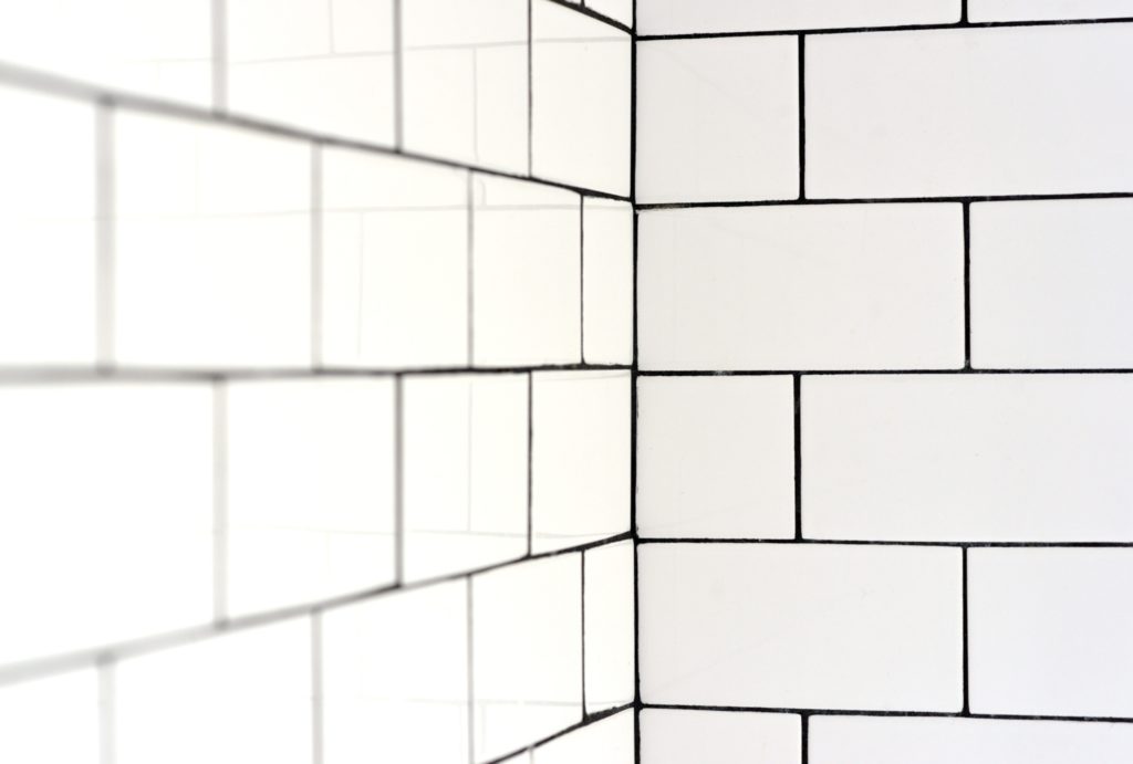 White dubway tiles in a hotel shower with dark colored grout.