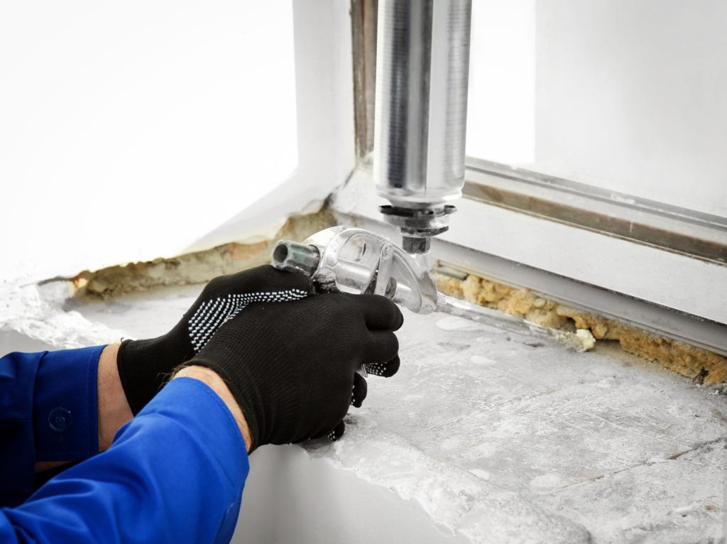 Construction worker repairing window in house using expandable foam caulk