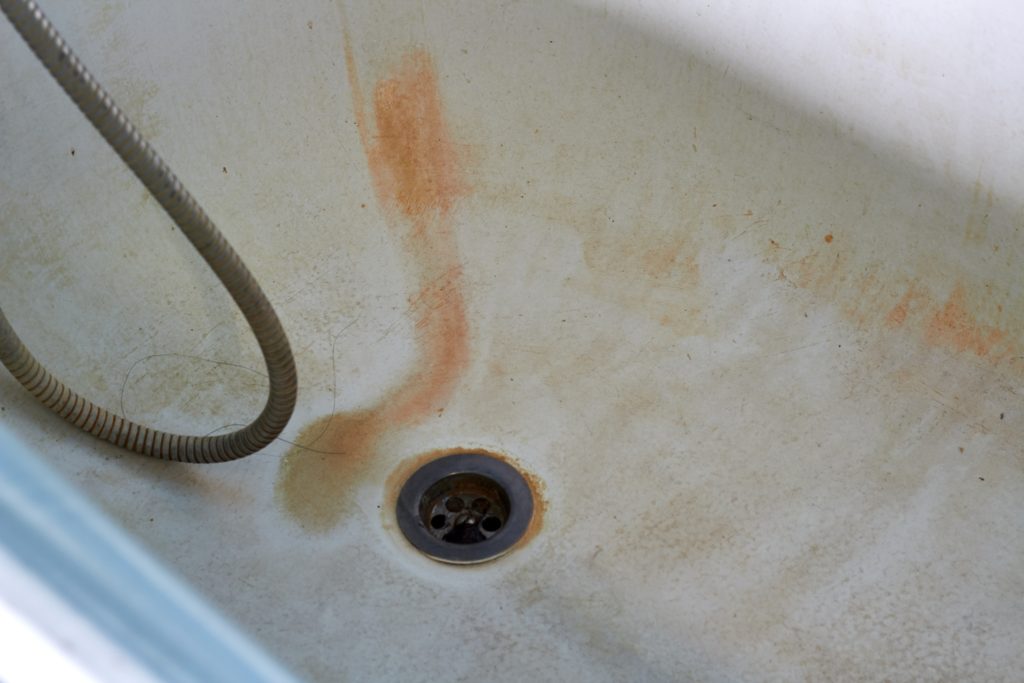 A hotel bathtub with rust stains and discoloration.