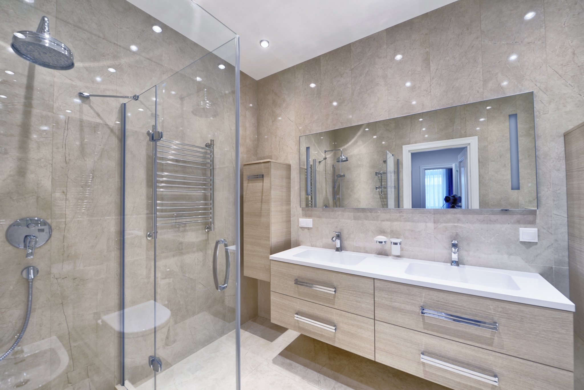 A bathroom with tan natural stone. Stone care is important when using it in hotel bathrooms.