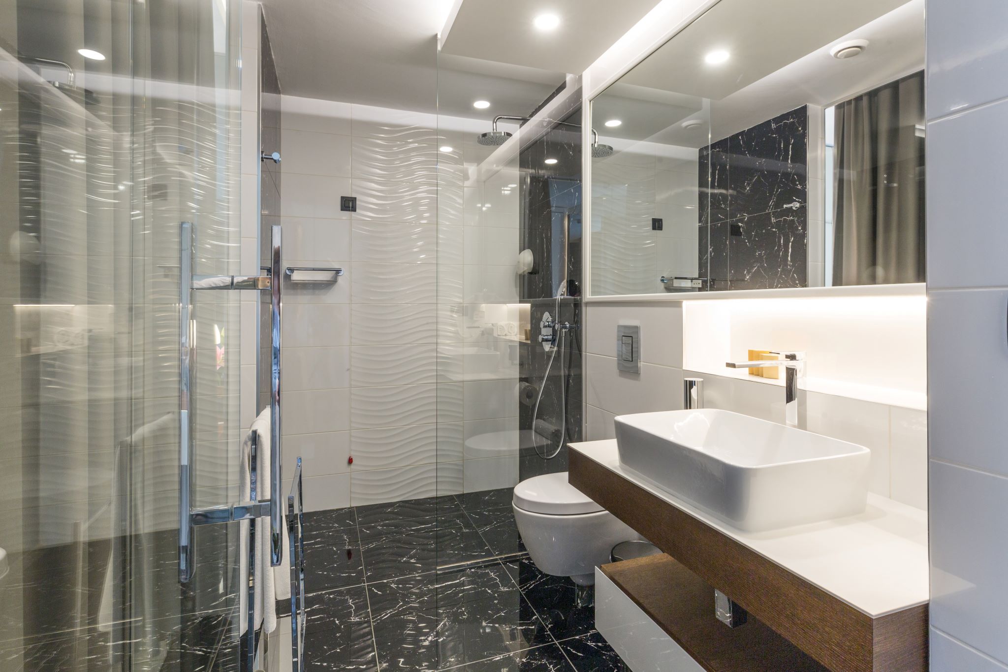 interior of a luxury hotel bathroom with glass shower and black marble floor